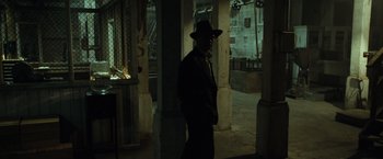 Movie still from “The Curious Case of Benjamin Button” (2008), directed by David Fincher – A man wearing a hat standing in a dark room; Wide shot, Low angle