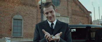 Movie still from “The Curious Case of Benjamin Button” (2008), directed by David Fincher – A man in a suit and tie holding a piece of food in his hands; Close Up shot, Low angle