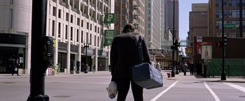 Movie still from “The Dark Knight” (2008), directed by Christopher Nolan – A man in a business suit walking down the street; Wide shot, Over the shoulder angle