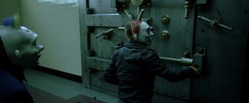 Movie still from “The Dark Knight” (2008), directed by Christopher Nolan – A man in a clown mask standing in front of a bank vault; Medium shot, High angle