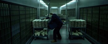 Movie still from “The Dark Knight” (2008), directed by Christopher Nolan – A person in a room filled with stacks of money; Wide shot, High angle