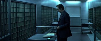 Movie still from “The Dark Knight” (2008), directed by Christopher Nolan – A man in a black suit is holding a sword; Medium shot, Low angle