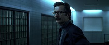 Movie still from “The Dark Knight” (2008), directed by Christopher Nolan – A man in a suit standing in front of a wall; Close Up shot, Low angle