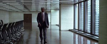Movie still from “The Dark Knight” (2008), directed by Christopher Nolan – A man in a suit and tie walking in an empty room; Wide shot, Low angle