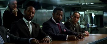 Movie still from “The Dark Knight” (2008), directed by Christopher Nolan – A group of men sitting at a wooden table; Medium shot, Low angle
