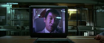 Movie still from “The Dark Knight” (2008), directed by Christopher Nolan – A man in a suit is on a television screen; Extreme Close Up shot, Low angle