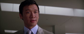 Movie still from “The Dark Knight” (2008), directed by Christopher Nolan – A person wearing a suit and tie; Close Up shot, Over the shoulder angle