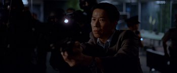 Movie still from “The Dark Knight” (2008), directed by Christopher Nolan – A man holding a camera in a dark room; Medium shot, Low angle