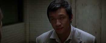 Movie still from “The Dark Knight” (2008), directed by Christopher Nolan – A person wearing a suit and tie; Close Up shot, High angle