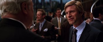 Movie still from “The Dark Knight” (2008), directed by Christopher Nolan – A group of men in suits and ties at a party; Close Up shot, Over the shoulder angle