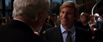Movie still from “The Dark Knight” (2008), directed by Christopher Nolan – A man in a business suit talking to another man in a business suit; Close Up shot, Over the shoulder angle