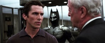 Movie still from “The Dark Knight” (2008), directed by Christopher Nolan – A man standing in front of a man in a batman suit; Medium shot, Over the shoulder angle