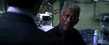 Movie still from “The Dark Knight” (2008), directed by Christopher Nolan – An older man wearing a suit and a tie; Close Up shot, Over the shoulder angle