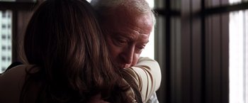 Movie still from “The Dark Knight” (2008), directed by Christopher Nolan – An older man and a younger woman hugging; Close Up shot, Over the shoulder angle