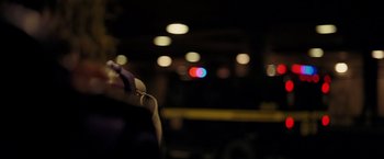 Movie still from “The Dark Knight” (2008), directed by Christopher Nolan – A blurry picture of a person holding a baseball bat; Close Up shot, Over the shoulder angle