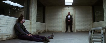 Movie still from “The Dark Knight” (2008), directed by Christopher Nolan – A man in a suit standing in front of another man in a suit; Wide shot, Low angle