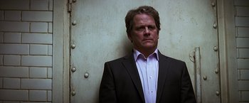 Movie still from “The Dark Knight” (2008), directed by Christopher Nolan – A man wearing a suit and tie standing in front of a wall; Close Up shot, Low angle