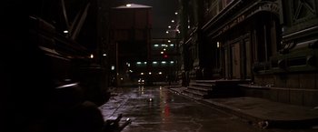 Movie still from “The Dark Knight” (2008), directed by Christopher Nolan – A dark street at night lit by street lights; Extreme Wide shot, High angle