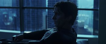 Movie still from “The Dark Knight” (2008), directed by Christopher Nolan – A man sitting in front of a window in a dark room; Close Up shot, Low angle