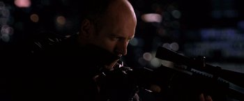 Movie still from “The Dark Knight” (2008), directed by Christopher Nolan – A bald man with a gun in his mouth; Close Up shot, Low angle