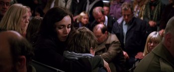 Movie still from “The Dark Knight” (2008), directed by Christopher Nolan – A woman and a boy are hugging in a crowded train; Medium shot, Over the shoulder angle