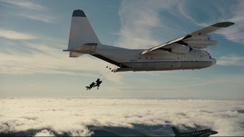 Movie still from “The Dark Knight Rises” (2012), directed by Christopher Nolan – A person is parachuting from a plane into the clouds; Extreme Wide shot, Low angle