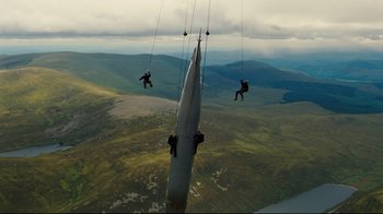 Movie still from “The Dark Knight Rises” (2012), directed by Christopher Nolan – A group of people hanging on to the side of an airplane; Extreme Wide shot, Low angle
