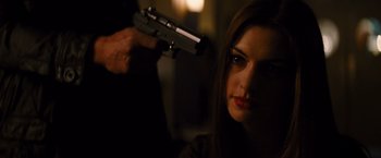 Movie still from “The Dark Knight Rises” (2012), directed by Christopher Nolan – A woman holding a gun up to her face; Close Up shot, Over the shoulder angle