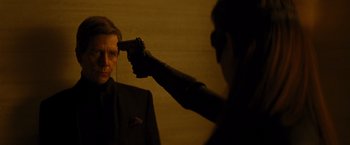 Movie still from “The Dark Knight Rises” (2012), directed by Christopher Nolan – A man holding a gun pointed at a man in a black suit; Close Up shot, Over the shoulder angle