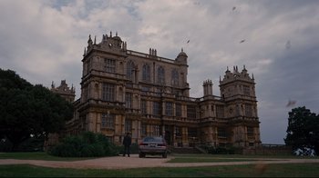 Movie still from “The Dark Knight Rises” (2012), directed by Christopher Nolan – A car parked in front of a large building; Extreme Wide shot, Low angle