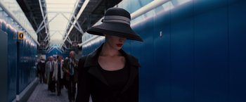 Movie still from “The Dark Knight Rises” (2012), directed by Christopher Nolan – A woman wearing a hat and a black jacket; Close Up shot, Low angle