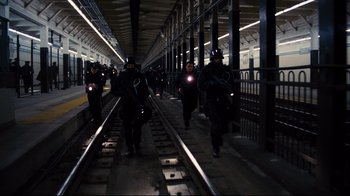 Movie still from “The Dark Knight Rises” (2012), directed by Christopher Nolan – A group of people walking on train tracks; Wide shot, High angle