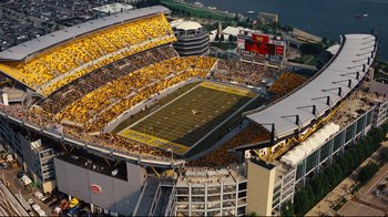 Movie still from “The Dark Knight Rises” (2012), directed by Christopher Nolan – An aerial view of a football stadium filled with fans; Extreme Wide shot, High angle