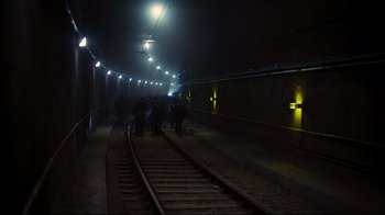 Movie still from “The Dark Knight Rises” (2012), directed by Christopher Nolan – A group of people standing on a train track in a tunnel; Extreme Wide shot, High angle