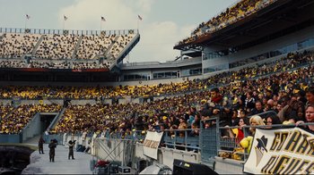 Movie still from “The Dark Knight Rises” (2012), directed by Christopher Nolan – A large crowd of people in a stadium; Extreme Wide shot, High angle