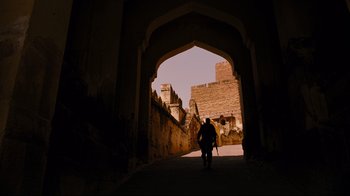 Movie still from “The Dark Knight Rises” (2012), directed by Christopher Nolan – A man walking through a tunnel in a city; Extreme Wide shot, Low angle