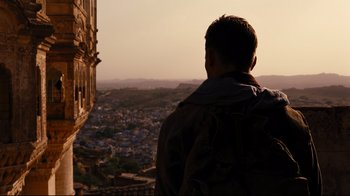 Movie still from “The Dark Knight Rises” (2012), directed by Christopher Nolan – A man looking out over a city at sunset; Wide shot, Low angle