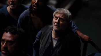 Movie still from “The Dark Knight Rises” (2012), directed by Christopher Nolan – A man with a gray beard is looking at the camera; Close Up shot, High angle