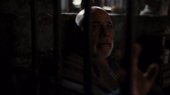 Movie still from “The Dark Knight Rises” (2012), directed by Christopher Nolan – An older man sitting in a chair with his eyes closed; Close Up shot, High angle