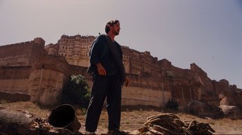 Movie still from “The Dark Knight Rises” (2012), directed by Christopher Nolan – A man standing in front of an old castle; Wide shot, Low angle
