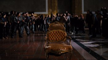 Movie still from “The Dark Knight Rises” (2012), directed by Christopher Nolan – An old chair in front of a group of people; Wide shot, High angle