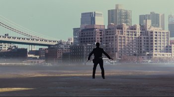 Movie still from “The Dark Knight Rises” (2012), directed by Christopher Nolan – A man standing in front of a large city; Extreme Wide shot, Low angle