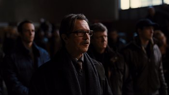 Movie still from “The Dark Knight Rises” (2012), directed by Christopher Nolan – A person wearing glasses and a scarf; Close Up shot, Low angle