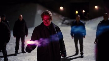 Movie still from “The Dark Knight Rises” (2012), directed by Christopher Nolan – A man in a black coat is holding a purple object; Medium shot, Over the shoulder angle