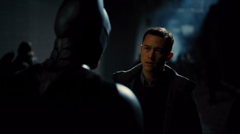 Movie still from “The Dark Knight Rises” (2012), directed by Christopher Nolan – A man talking to another man in a dark room; Close Up shot, Over the shoulder angle