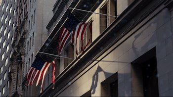 Movie still from “The Dark Knight Rises” (2012), directed by Christopher Nolan – Three american flags are hanging on a building's awning; Extreme Wide shot, Low angle