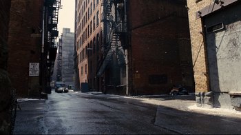 Movie still from “The Dark Knight Rises” (2012), directed by Christopher Nolan – An empty street with a fire escape on the side of the building; Extreme Wide shot, High angle