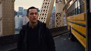 Movie still from “The Dark Knight Rises” (2012), directed by Christopher Nolan – A man standing in front of a bridge with buildings in the background; Medium shot, Over the shoulder angle