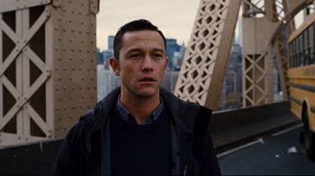 Movie still from “The Dark Knight Rises” (2012), directed by Christopher Nolan – A man standing on top of a bridge with buildings in the background; Close Up shot, Over the shoulder angle