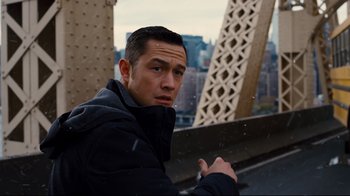 Movie still from “The Dark Knight Rises” (2012), directed by Christopher Nolan – A man in a black jacket standing next to a bridge; Close Up shot, Over the shoulder angle